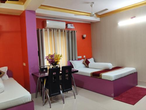 a room with two beds and a table and chairs at Relax Hotel in Bāghdogra