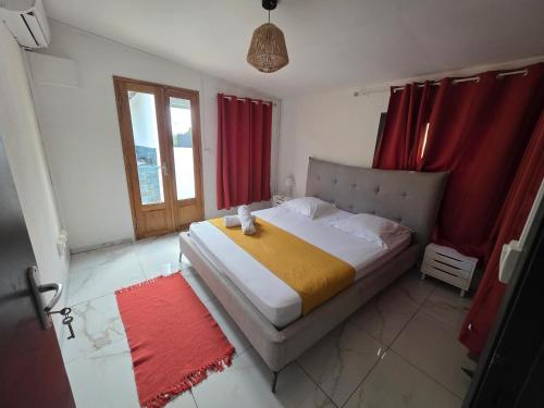 a bedroom with a large bed with red curtains at La Petite Case Tomi in Saint-Louis