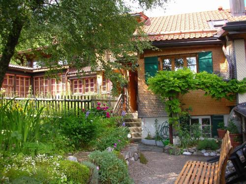 une maison avec un jardin et un banc devant. dans l'établissement Fauvettes, à Château-d'Oex