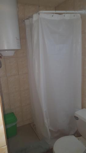a bathroom with a toilet and a white shower curtain at Bodega Habitable in La Serena