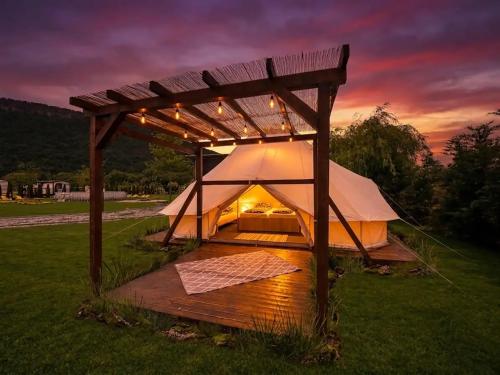a large tent in a field with a sunset in the background at Green Resort Suncuius in Şuncuiuş
