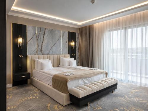 a bedroom with a large bed and a large window at Grand Hotel President in Baile Felix