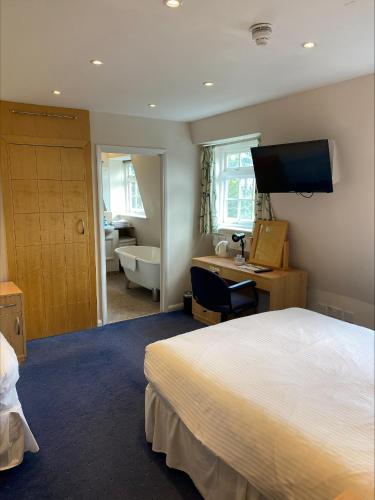 a bedroom with a bed and a desk and a bathroom at Lysses House Hotel in Fareham