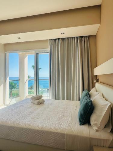 a bedroom with a large bed with a large window at Saradari Beach Hotel - Adults Only in Hersonissos