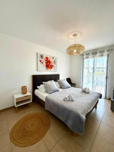 a bedroom with a large bed and a chandelier at T2 de standing front de mer in Propriano