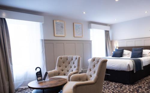 a bedroom with a bed and two chairs at Allerdale Court Hotel in Cockermouth
