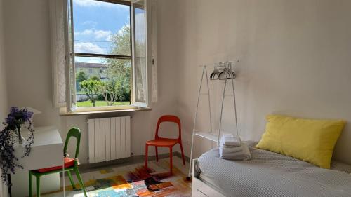 a bedroom with a bed and a chair and a window at La Casa di Katia in Pisa