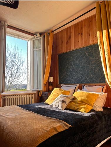a bedroom with a bed with yellow pillows and a window at La chambre magique in Masseret