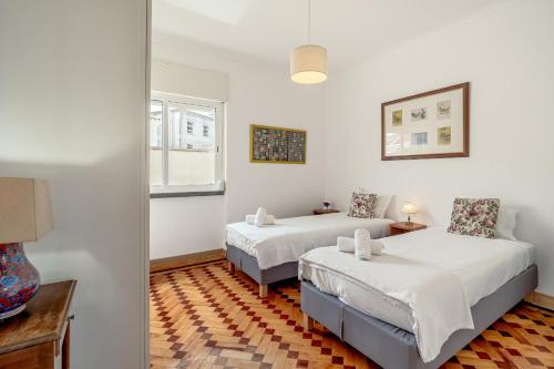 a bedroom with two beds and a table and a window at Santarem Terrace by Homing in Santarém