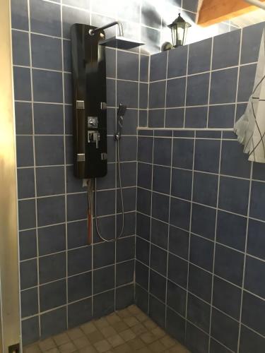 a blue tiled bathroom with a soap dispenser on the wall at Seul au Monde in Guizengeard