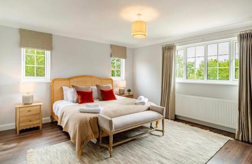 a bedroom with a large bed with red pillows at Dalforth Thaxted Barn Collection in London Stansted Airport
