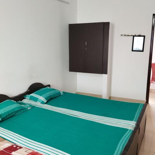 a bedroom with a bed with green sheets and a cabinet at Shifa Home Near Apollo Sankara Nethralaya Main Hospital in Chennai