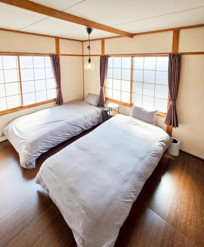 two beds in a room with two windows at Snow Veil Iwamizawa in Iwamizawa