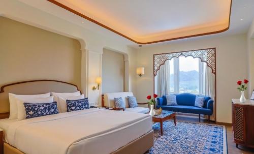 a bedroom with a large bed and a blue chair at Bhagirathi By Atishay in Haridwār
