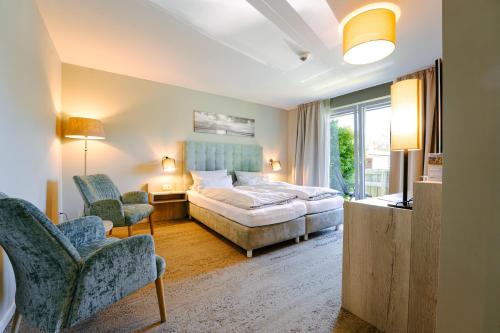 a hotel room with a bed and two chairs at Hotel Waastwinj in Utersum