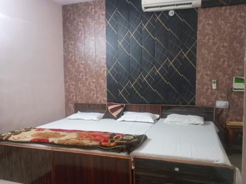 a bedroom with two beds and a wall at Braj Pushp Guest House in Mathura