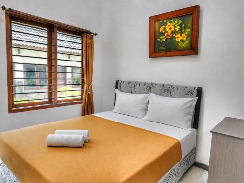 a bedroom with a bed with a yellow blanket and a window at Bawangan Express in Ngadisari
