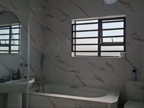 a bathroom with a tub and a sink and a window at Ficus self catering in Burgersfort