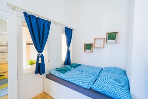 a bedroom with a blue bed with a window at Corso Apartman in Siófok