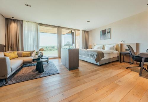 a hotel room with a bed and a living room at Severins Resort & Spa Öschberghof in Donaueschingen