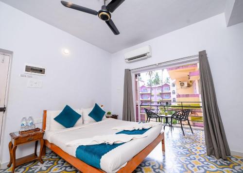 a bedroom with a bed and a balcony at Joystays Renton Manor in Arpora