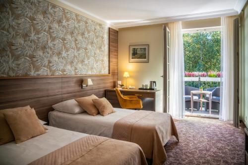 a hotel room with two beds and a balcony at Korona Hotel in Ostrołęka