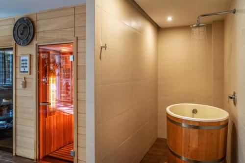 a bathroom with a tub and a clock on the wall at Korona Hotel in Ostrołęka