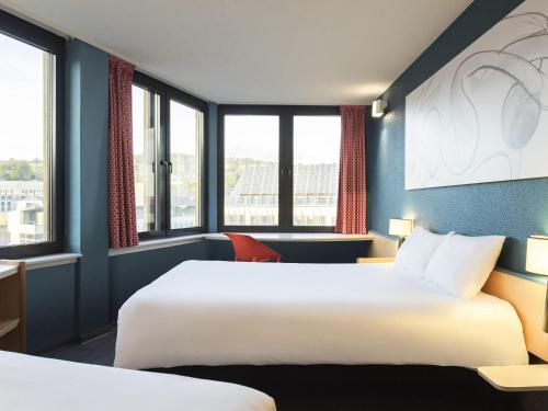 a hotel room with two beds and windows at ibis Liège Centre Opéra in Liège