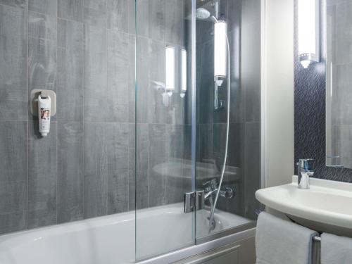 a bathroom with a glass shower and a sink at ibis Liège Centre Opéra in Liège