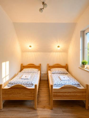two beds in a room with two windows at Domek z balią Pod Dębem in Zabrzeź