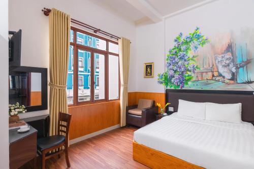 a bedroom with a bed and a desk and a window at Grand Center Da Lat by Lilly Hotel in Da Lat