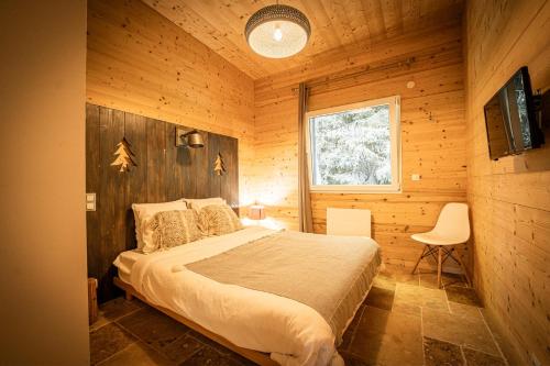 a bedroom with a bed in a wooden cabin at chalets 4 - les jolis chalets in Barbey-Séroux