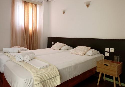 two beds in a hotel room with towels on them at Galanopoulos Hotel in Loutraki