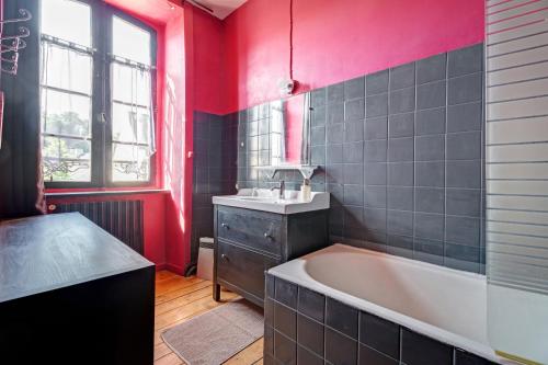 a bathroom with a tub and a sink and red walls at Maison le 28 in Jugon Les Lacs