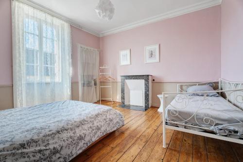 a bedroom with pink walls and a bed and a fireplace at Maison le 28 in Jugon Les Lacs