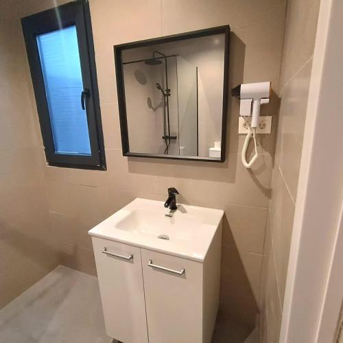 a bathroom with a white sink and a mirror at Apartamentos ATARAZANAS in Málaga
