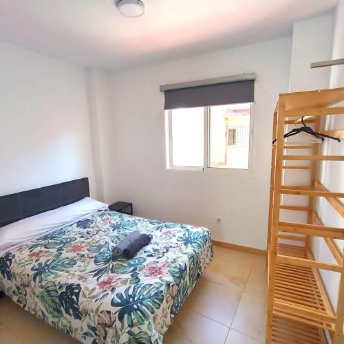 a bedroom with a bed with a floral bedspread and a ladder at Apartamentos ATARAZANAS in Málaga