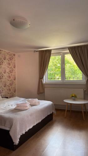 a bedroom with a bed and a table and two windows at Marginimea Sibiului - Pensiunea Darian & David in Orlat