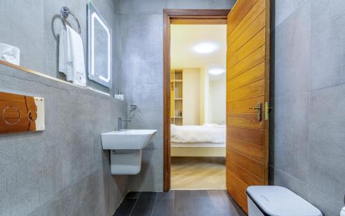 a bathroom with a sink and a toilet and a door at Kika Des Hotel Suites - Serviced Apartments, Westland, Nairobi in Nairobi