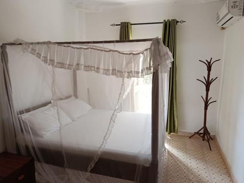 a bed with a canopy in a room with a window at Peaceful Diani apartment in Diani Beach