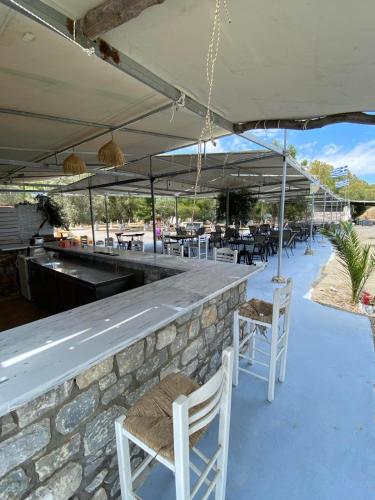 a bar with white chairs and a stone wall at Camping Dias in Gythio