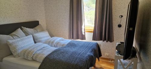 a bedroom with a bed with a blue blanket and a window at Apartment in peacefull surroundings in Ådnavik
