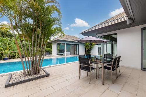 a patio with a table and chairs next to a pool at 4BR Luxury Pool Retreat - Villa Azura Nai Harn in Nai Harn Beach