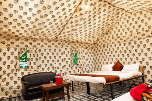 a bedroom with a bed and a chair in a room at Vanveli The Forest Resort in Sasan Gir