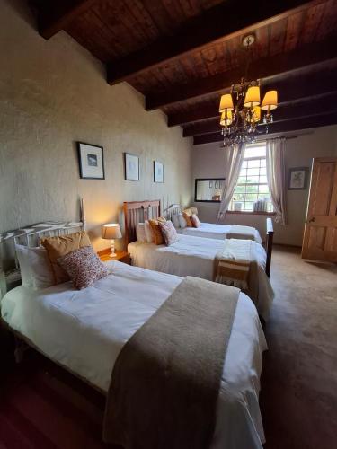 a bedroom with three beds and a chandelier at Thali Thali Game Lodge in Langebaan