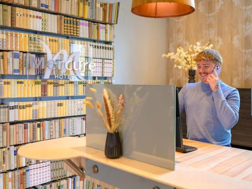 a man talking on a cell phone in a library at Mercure Hotel Hannover City in Hannover