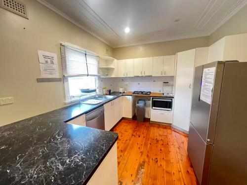 a kitchen with white cabinets and a black counter top at Room 78 in Merrylands