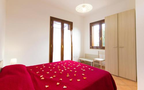 a bedroom with a red bed with a red blanket with flowers at Appartamenti Elios in Birgi Vecchi