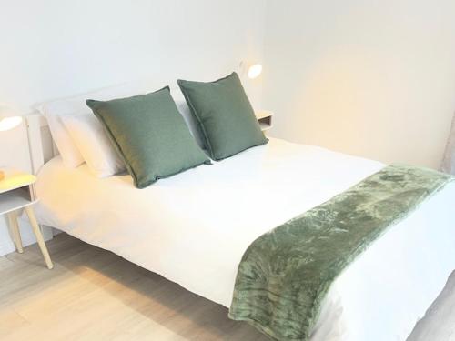 a white bed with green pillows in a bedroom at Net Dankbaar in De Kelders