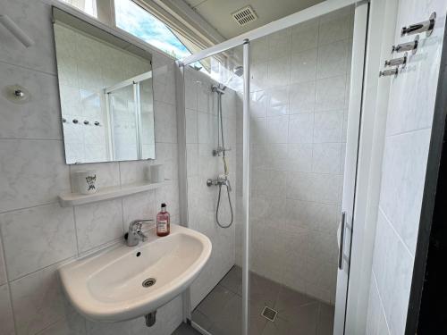 a white bathroom with a sink and a shower at Keizerskroon 239 in Julianadorp